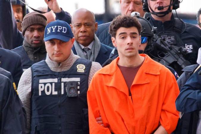 Luigi Mangione, the suspect in the murder of UnitedHealth Group executive Brian Thompson, arrives at a helicopter pad after being extradited from Pennsylvania, as New York Mayor Eric Adams walks behind him, in New York, U.S. Reuterspix