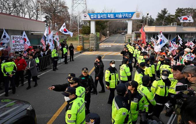 Police stand guard as supporters of arrested and impeached South Korean President Yoon Suk Yeol gather outside the Seoul Detention Center in Uiwang on March 7, 2025. A South Korean court cancelled the arrest warrant of impeached President Yoon Suk Yeol on March 7, his lawyers said, but he remains behind bars with the prosecution set to appeal. - JUNG YEON-JE / AFP