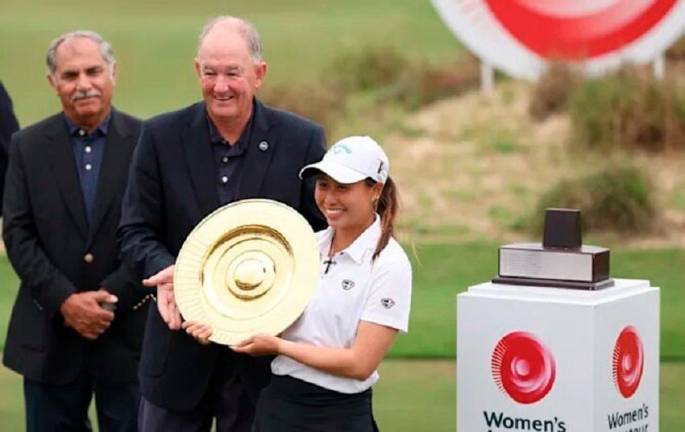 APGC Chairman Taimur Hassan Amin (left) and Niall Farquharson, Chairman of The R&amp;A, look on as Jeneath Wong (right) hoists the Women’s Amateur Asia-Pacific trophy. – The R&amp;A/Getty Images.