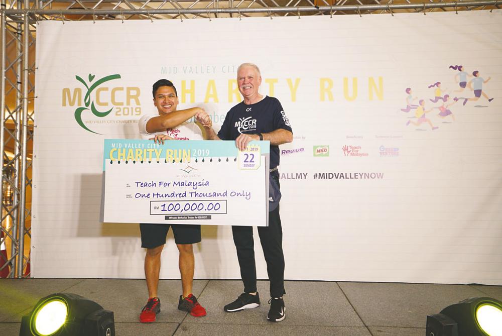 Dzameer (left) receiving the mock cheque from Barragry.
