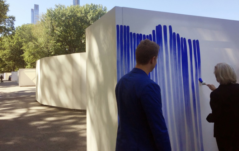 Danish artist Jeppe Hein (L) watches a woman paint lines on his installation entitled “Breathe with Me” in Central Park. — AFP