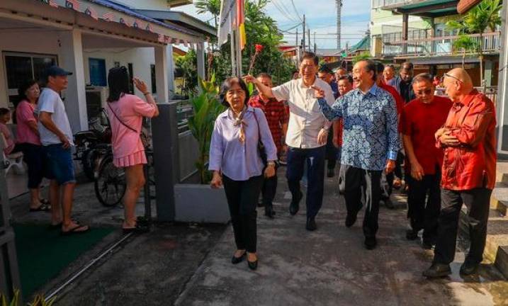 Tan, guided by Lim (white shirt), visits a village in Pulau Ketam during his first visit to the island. - AMIRUL SHAFIQ / THESUN