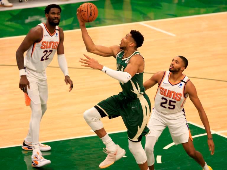 Milwaukee’s Giannis Antetokounmpo, center, drives past Phoenix’s Mikal Bridges, right, for a layup as the Bucks beat the visiting Suns 120-100 in game three of the NBA Finals on Sunday. — AFP
