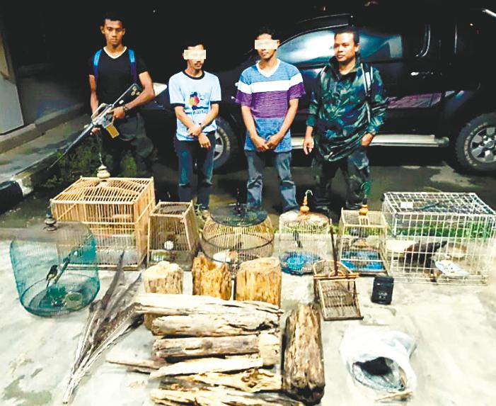 Rangers guarding two suspected poachers and some seized items.