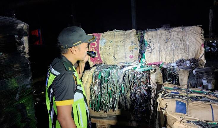An enforcement officer examining the illegal e-waste stored at the premises. – PIC COURTESY OF Kedah Department of Environment