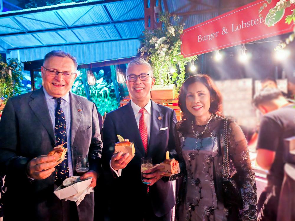 Enjoying mini lobster rolls at the BHC’s King’s Birthday Party are Charles Hay, Tengku Zafrul Tengku Abdul Aziz and Datuk Sri Kay Atisha Parasuraman.