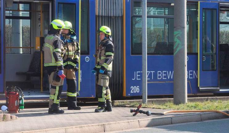 Fire fighters stand near a tram in Gera on March 16, 2025. German police said they are hunting a man who doused a woman tram passenger with flammable liquid and set fire to her, causing critical wounds. AFPpixS