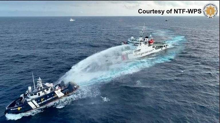 This handout taken and released on December 4, 2024 by the National Task Force for the West Philippine Sea (NTF-WPS) shows a China Coast Guard ship (R) deploying water cannon at the Phillipine Bureau of Fisheries and Aquatic Resources (BFAR) vessel BRP Datu Pagbuaya (L) near Scarborough Shoal in disputed waters of the South China Sea. The Philippines said the China Coast Guard fired water cannon December 4 on a government vessel during a maritime patrol near the disputed Scarborough Shoal. - AFP PHOTO / National Task Force for the West Philippine Sea (NTF-WPS)