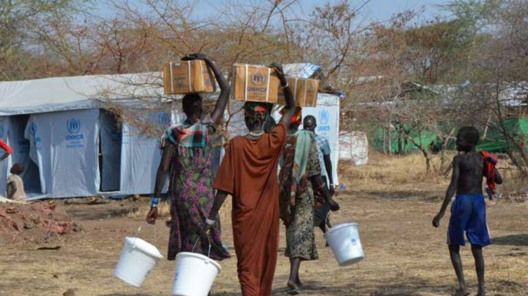 South Sudanese refugees, who fled to Ethiopia after internal ethnical conflicts erupted in their homeland in December 2013, carry essential aid items back to their tents in Kule Camp. - UNHCR