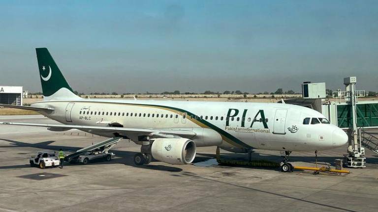 View of a Pakistan International Airlines (PIA) passenger plane, taken through a glass panel, at Islamabad International Airport, Pakistan October 3, 2023. - REUTERSPIX