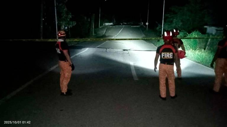 Rescue personnel stand in front of a crack in a road caused by a magnitude 6.9 quake, in Daanbantayan, Cebu Province, Philippines, October 1, 2025. - Municipality of Daanbantayan/Handout via REUTERSPIX