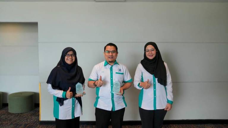 Ikram Ramli (centre) with the 4-Star CIDB Score Award. The other two are employees of UMPSA Services.