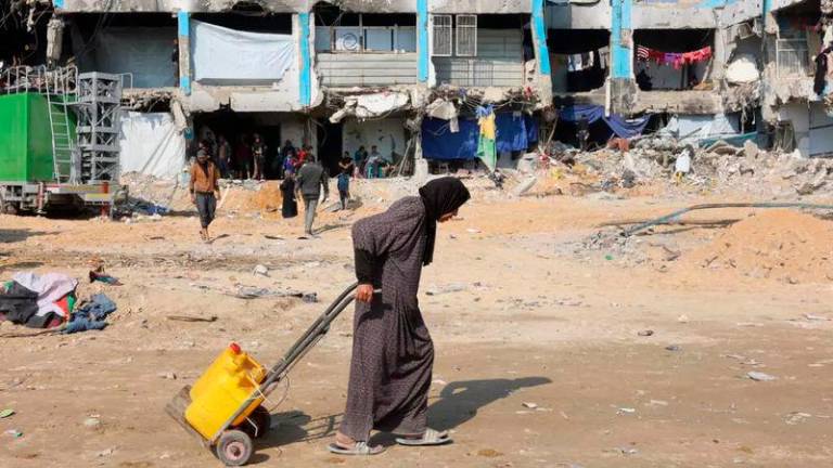 A Palestinian woman pulls a trolley with water cans in Jabalia in the northern Gaza Strip © Omar AL-QATTAA / AFP