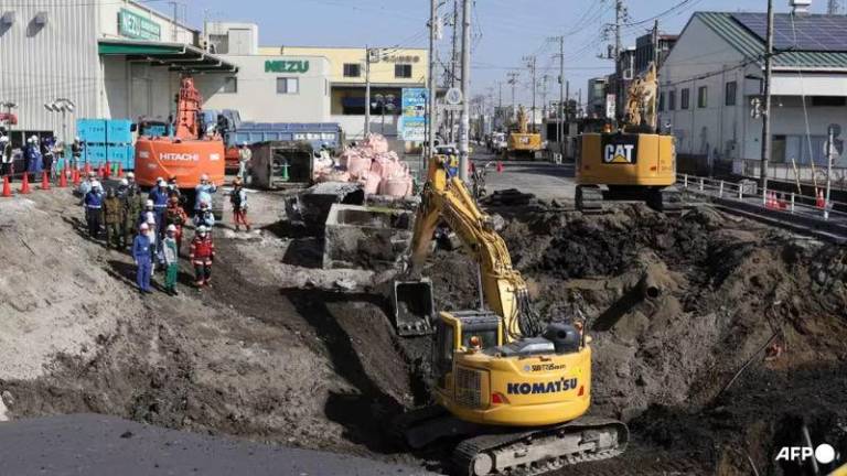 Excavators and rescue personnel working to construct a slope for rescue operations - AFPpix