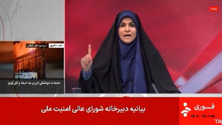 This image grab taken from footage broadcast by Iran’s IRINN news on June 16, 2025, shows a news reporter gesturing as she presents the news seconds before a loud explosion. The Islamic Republic of Iran Broadcasting (IRIB) building was struck in an Israeli attack on June 16, cutting live coverage immediately. The blast occurred as the presenter was live on TV lambasting Israel before she was seen leaving the live broadcast, Iranian media reported, sharing a video of the incident. - AFP PHOTO / IRINN