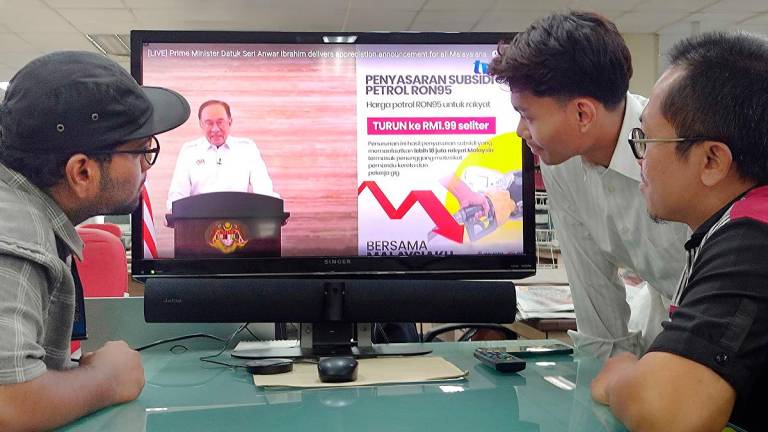 A group of man watches televisions as Malaysian Prime Minister Anwar Ibrahim addresses the nation during a live telecast. - SYED AZAHAR SYED OSMAN THESUN