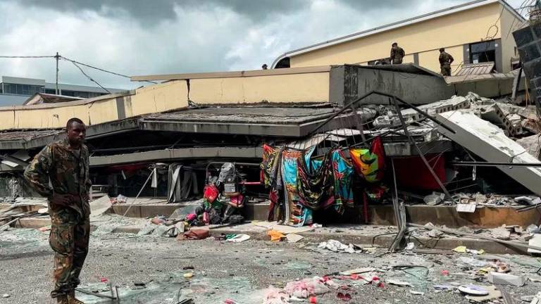 This screengrab taken from handout video footage posted on the Facebook account of Michael Thompson on December 17, 2024 shows a member of security inspecting a collapsed building in Vanuatu's capital Port Vila after a powerful earthquake hit the Pacific island. - AFPPIX