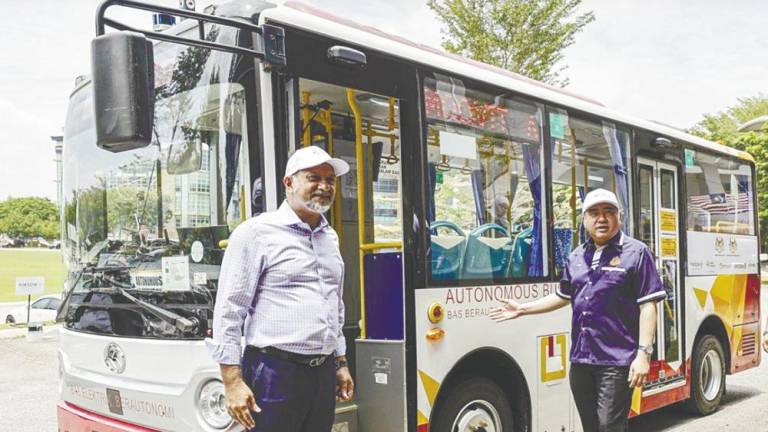 Gobind (left) and Loke with a 5G-enabled autonomous bus during a use-case demonstration at Futurise Centre. – Bernamapic