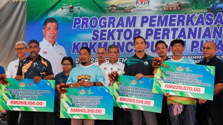 Minister of Agriculture and Food Security, Datuk Seri Mohamad Sabu (centre), with recipients of assistance under the Agricultural Sector Empowerment Programme by the Ministry of Agriculture and Food Security at the Kampung Labuh Banting Flood Resettlement Centre today. – BERNAMA