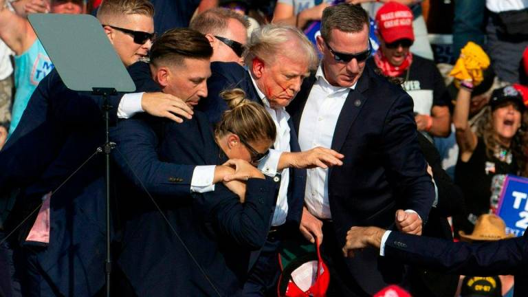FILEpi - Donald Trump is seen with blood on his face surrounded by secret service agents at a campaign event at Pennsylvania - AFP