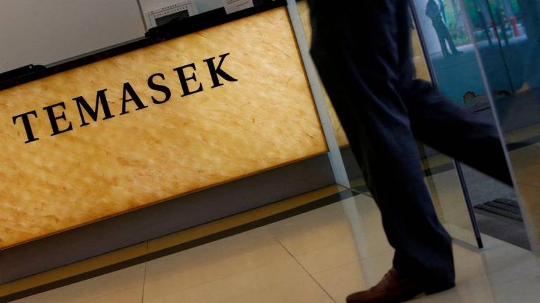 FILE PHOTO: A man passes a logo of state investor Temasek Holdings at their office in Singapore July 8, 2014. REUTERS/Edgar Su/File Photo/File Photo