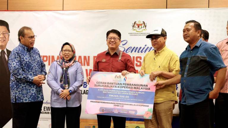 Menteri Pembangunan Usahawan dan Koperasi Datuk Ewon Benedick (tengah) menyampaikan Geran Bantuan Pembangunan Suruhanjaya Koperasi Malaysia kepada wakil Koperasi Pembangunan Tanah Sungai Matanggar Beluran Berhad bernilai RM265,500 pada Majlis Penutupan Seminar Kepimpinan dan Keusahawanan Koperasi Wanita Sabah hari ini. - BERNAMA