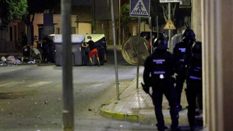 People move dumpsters on a road as police officers keep watch, amid anti-migrant unrest following an attack on an elderly man by unknown assailants earlier in the week, in Torre Pacheco, Spain, July 13, 2025. REUTERS/Violeta Santos Moura