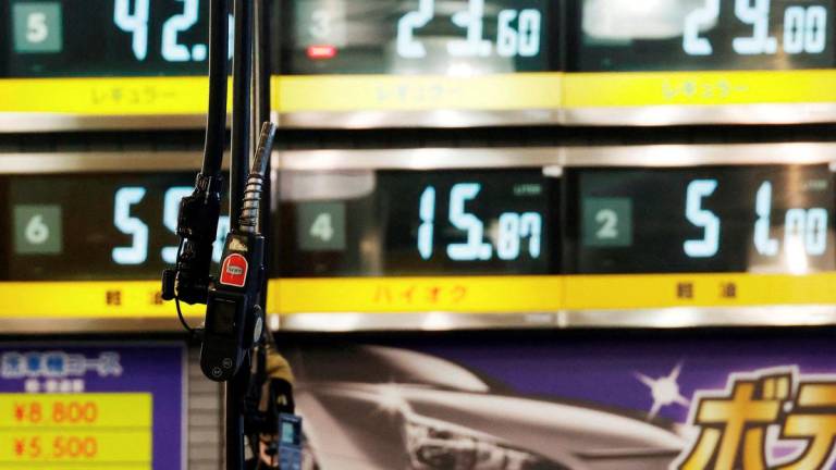 Gasoline fuel guns are pictured in front of fuel boards at a gasoline station in Tokyo, Japan September 20, 2022. - REUTERS