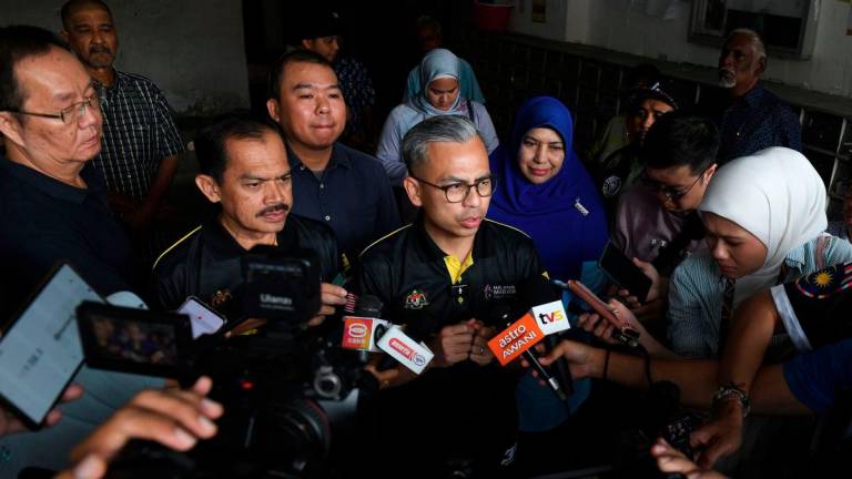 Communications Minister Datuk Fahmi Fadzil speaks to the media after presenting the Tabung Kasih@HAWANA aid to Kwong Wah Yit Poh journalist, Choo Kar Chun, 44, at the journalist’s residence in Air Itam today. – BERNAMA
