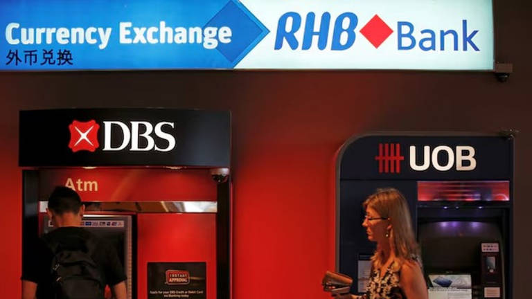 A man uses a DBS automated teller machine next to a United Overseas Banking (UOB) teller, near an RHB Capital Bhd currency exchange booth in Singapore January 5, 2016. - REUTERS