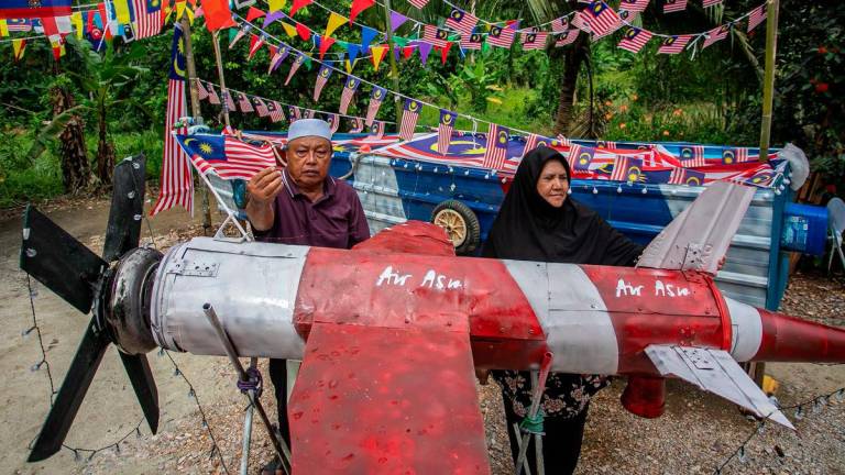 Ahmad Ali Mingan 72 (kiri) bersama isterinya Fauziah Kamarudin 62, menghiasi halaman rumah mereka dengan replika kapal terbang dan sampan yang diperbuat daripada barangan terpakai sempena Program Halaman Rumah Merdeka Peringkat Kampung anjuran pusat perkhemahan dan rekreasi, Gopeng Glamping Park di Kampung Chulek, semalam - fotoBERNAMA