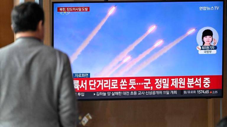 A man watches a television screen showing a news broadcast with file footage of a North Korean missile test, at a train station in Seoul on March 10, 2025. REUTERSpix.