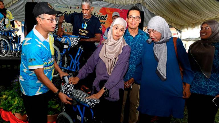 The Deputy Chief Minister I of Penang, Datuk Dr Mohamad Abdul Hamid (left), presented a wheelchair to Nur Hasliza Abdullah, 29, at the “People’s Carnival with Deputy Chief Minister I: Takaful Goes to the Village” tour stop held at Sungai Ara Secondary School today. Also present was the Chief Executive Officer of the Malaysian Takaful Association (MTA), Mohd Radzuan Mohamed (third from right). - BERNAMA