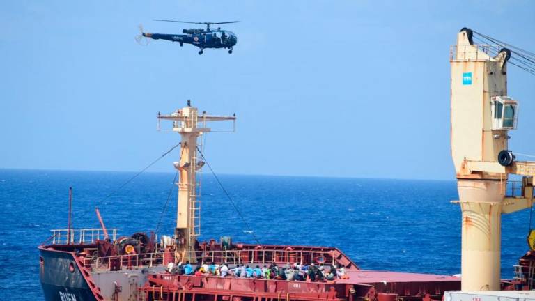 This picture shared by the Indian Navy on the X platform on March 16, 2024 shows people on board of the recaptured Maltese ship the MV Ruen, as an Indian Naval helicopter flies overhead. India’s Navy has recaptured the ship from Somali pirates off the Indian coast on March 16, 2024/AFPPix