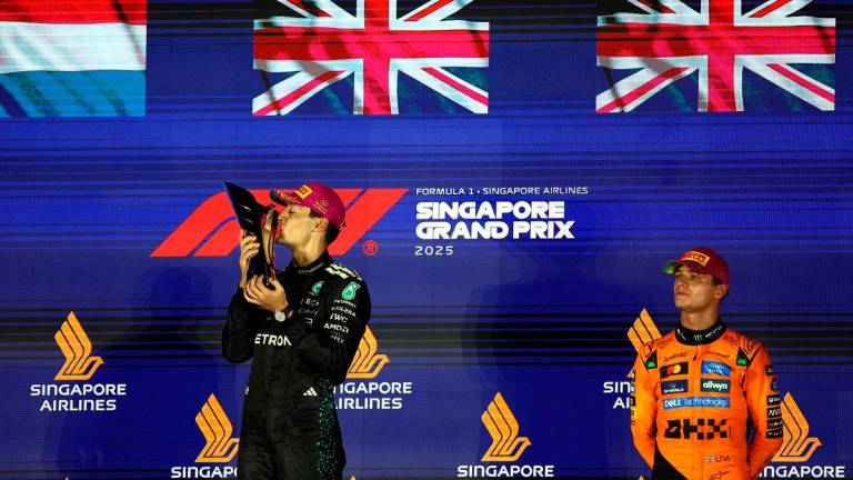George Russell celebrates on the podium with the trophy after winning the Singapore Grand Prix with third placed McLaren’s Lando Norris. - REUTERS/Edgar Su