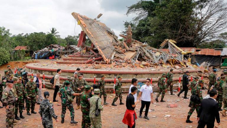 Military attaches and diplomats from 13 countries observe the implementation of the Cambodia–Thailand ceasefire agreement next to a destroyed building by the An Ses border checkpoint in Cambodia’s Preah Vihear province on July 30, 2025. - Chor Sokunthea / AFP