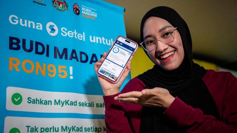 Penerima manfaat BUDI95, Rania Ardini Mohd Asri, menunjukan aplikasi Setel sewaktu menggunakan inisiatif BUDI95 ketika tinjauan di Stesen Minyak di Jalan Sultan Azlan Shah awal pagi ini. - fotoBERNAMA