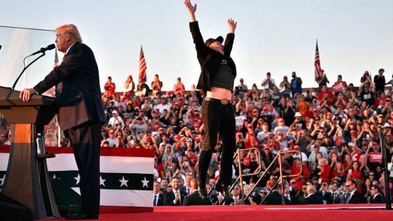 Tesla CEO Elon Musk (R) jumps on stage as he joins former US President and Republican presidential candidate Donald Trump during a campaign rally at site of his first assassination attempt in Butler, Pennsylvania on October 5