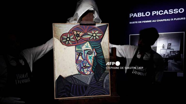 Employees unveal a painting by French artist Pablo Picasso titled Bust of a woman with a flowery hat and featuring one his lovers Dora Maar, during its presentation at Hotel Drouot auction house on September 18, 2025. - AFP