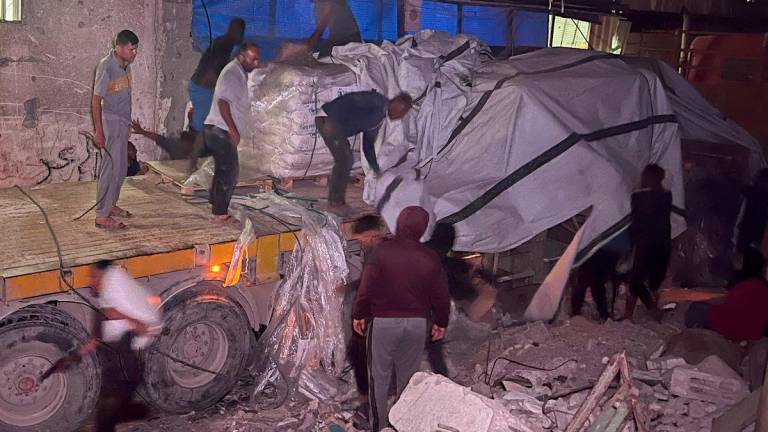 Palestinian workers unload sacks of flour from an aid truck at a bakery, in Khan Younis, southern Gaza Strip, May 21, 2025. - REUTERSPIX