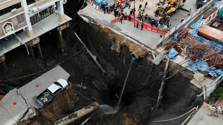 A vehicle teeters on the edge of a massive sinkhole that opened on Samsen Road near Vajira Hospital, in Bangkok, Thailand, September 24, 2025. - REUTERSPIX