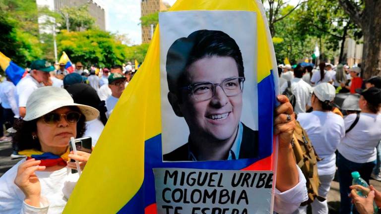 A woman holds a national flag during the so-called “Silent March” to show support for the health of Senator Miguel Uribe Turbay and to call for peace for the country in Medellin, Colombia, on June 15, 2025. Uribe, a 39-year-old conservative senator, was shot twice in the head and once in the leg while giving a speech in a park on June 7 in western Bogota. - JAIME SALDARRIAGA / AFP