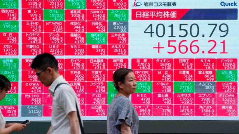 Pedestrians walk in front of an electronic quotation board displaying the Nikkei Stock Average closing price at 40,000 yen level on the Tokyo Stock Exchange in Tokyo on June 27, 2025. - AFPPIX
