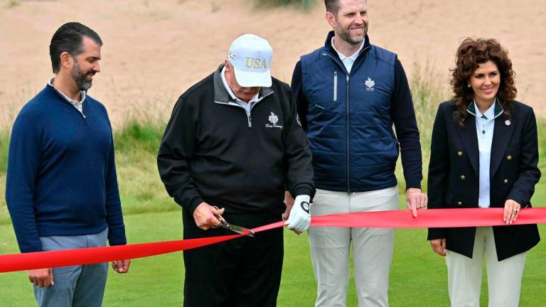 US President Donald Trump (2L), flanked by his sons Eric Trump (2R) and Donald Trump Jr. (L), along with Trump International Golf Links Executive Vice President Sarah Malone cuts the ribbon on the first tee to officially open the Trump International Golf Links course in Balmedie, Aberdeenshire.