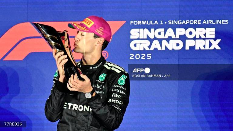 First-placed Mercedes' British driver George Russell celebrates on the podium after the Formula One Singapore Grand Prix night race at the Marina Bay Street Circuit in Singapore on October 5, 2025. - AFP