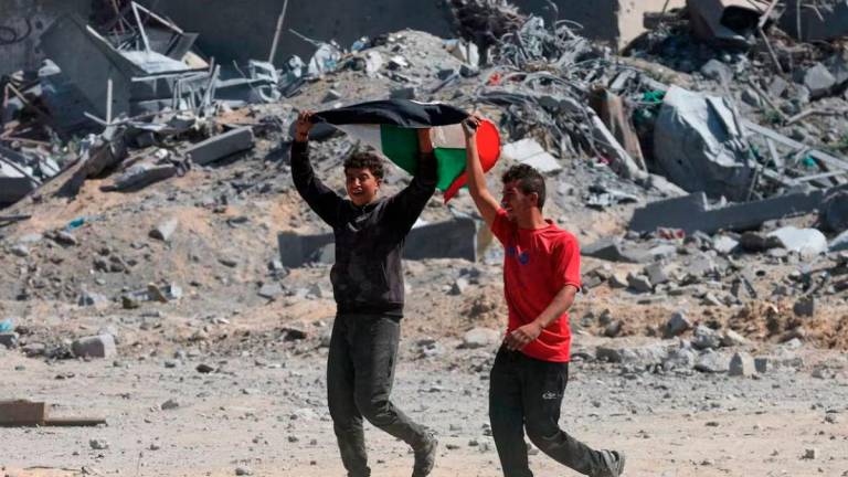 Palestinians react near rubble following Israeli forces’ withdrawal from the area, after Israel and Hamas agreed on the Gaza ceasefire, in Khan Younis, in the southern Gaza Strip, October 10, 2025. - REUTERS