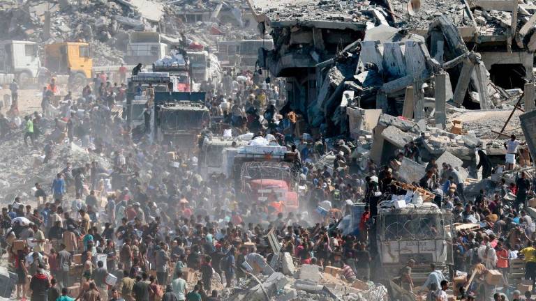 Palestinians collect aid supplies from trucks that entered Gaza, amid a ceasefire between Israel and Hamas, in Khan Younis, in the southern Gaza Strip October 12, 2025. REUTERS/Ramadan Abed