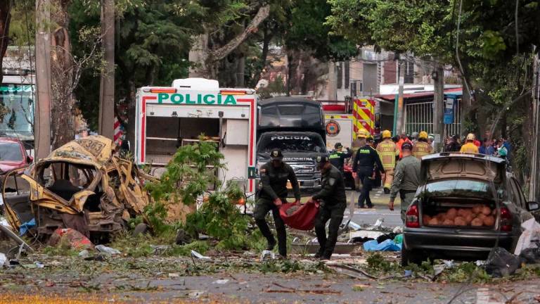 Police officers carry debris from the site of a bomb explosion in cali, Colombia on August 21 2025. Five people were killed and dozens were injured when a vehicle bomb targeted a military base on a busy street in the Colombian city of Cali on August 21, 2025, local authorities said. (Photo by Iusef Samir Rojas / AFP)
