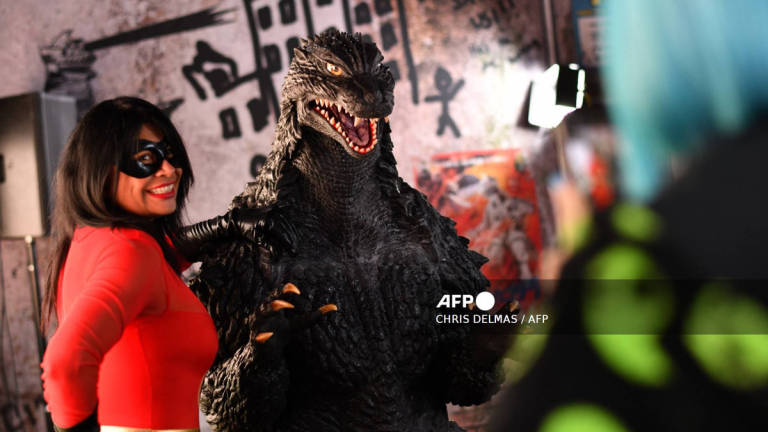 An attendee poses for photos with Godzilla during Comic-Con International in San Diego, California, on July 26, 2025. - AFP