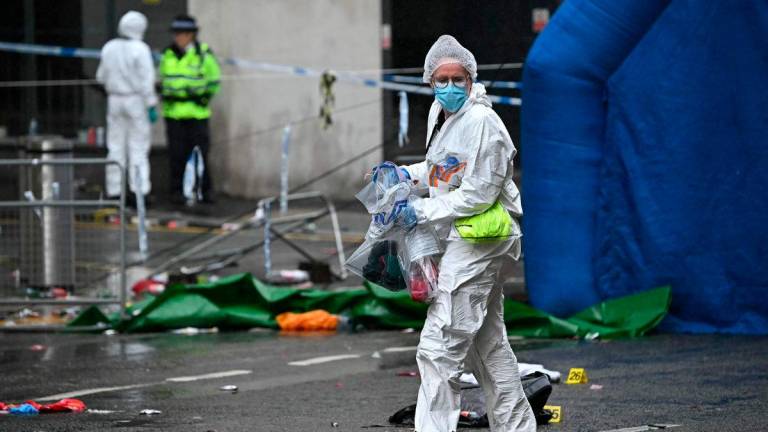 A Police forensics officer carries items bagged for evidence as they work at the scene on Water Street in Liverpool, north-west England on May 27, 2025,. AFPpix